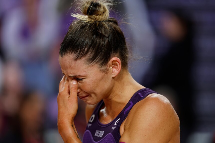 A player holds their hand over their eyes as they cry