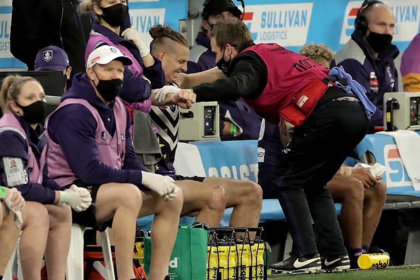 Nat Fyfe sits on the bench receiving treatment from a doctor on his injured right shoulder