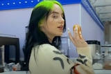 Billie Eilish holding a donut in profile in a still from the 'therefore i am' 2020 music video