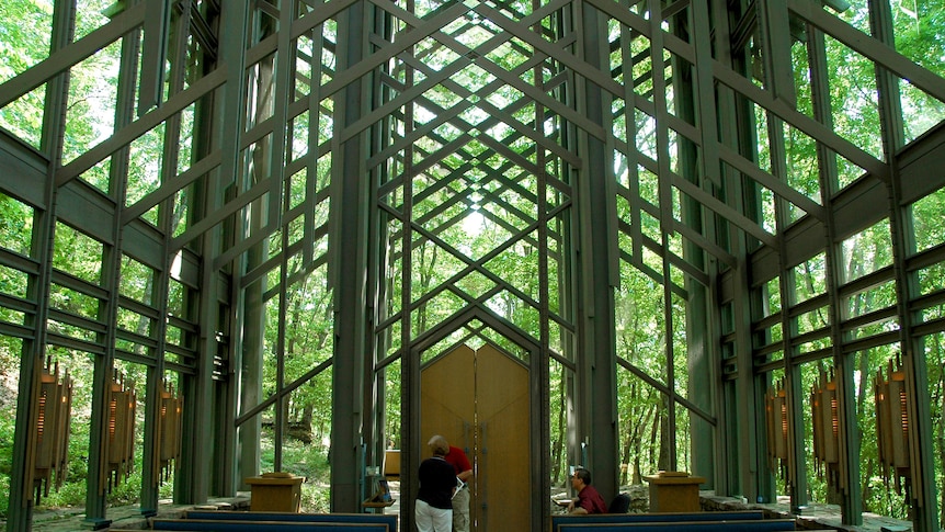 From the centre aisle, you view a dramatic wooden chapel atrium that is exposed to a forest canopy.