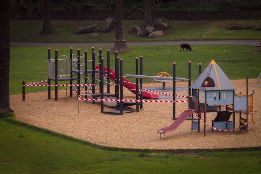 Red and white tape surrounds playground equipment.