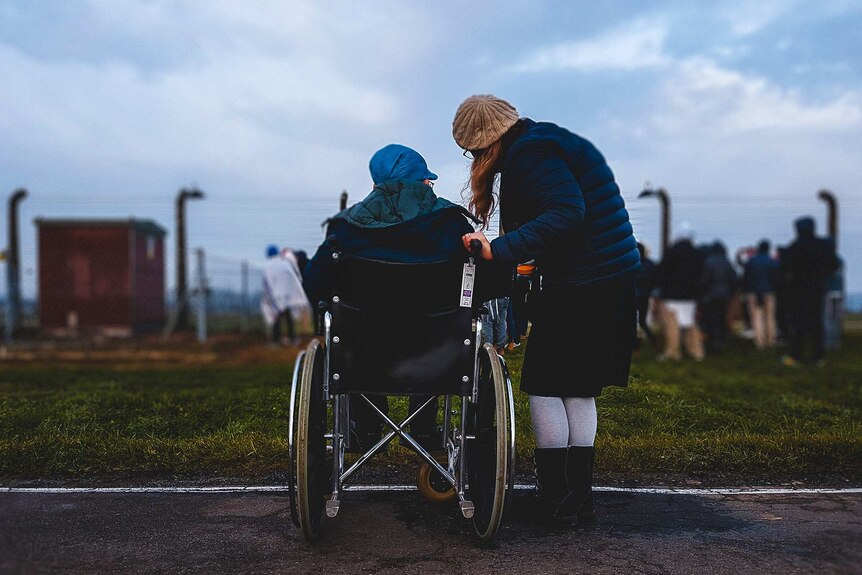Older person in wheelchair with a carer looking out at the races