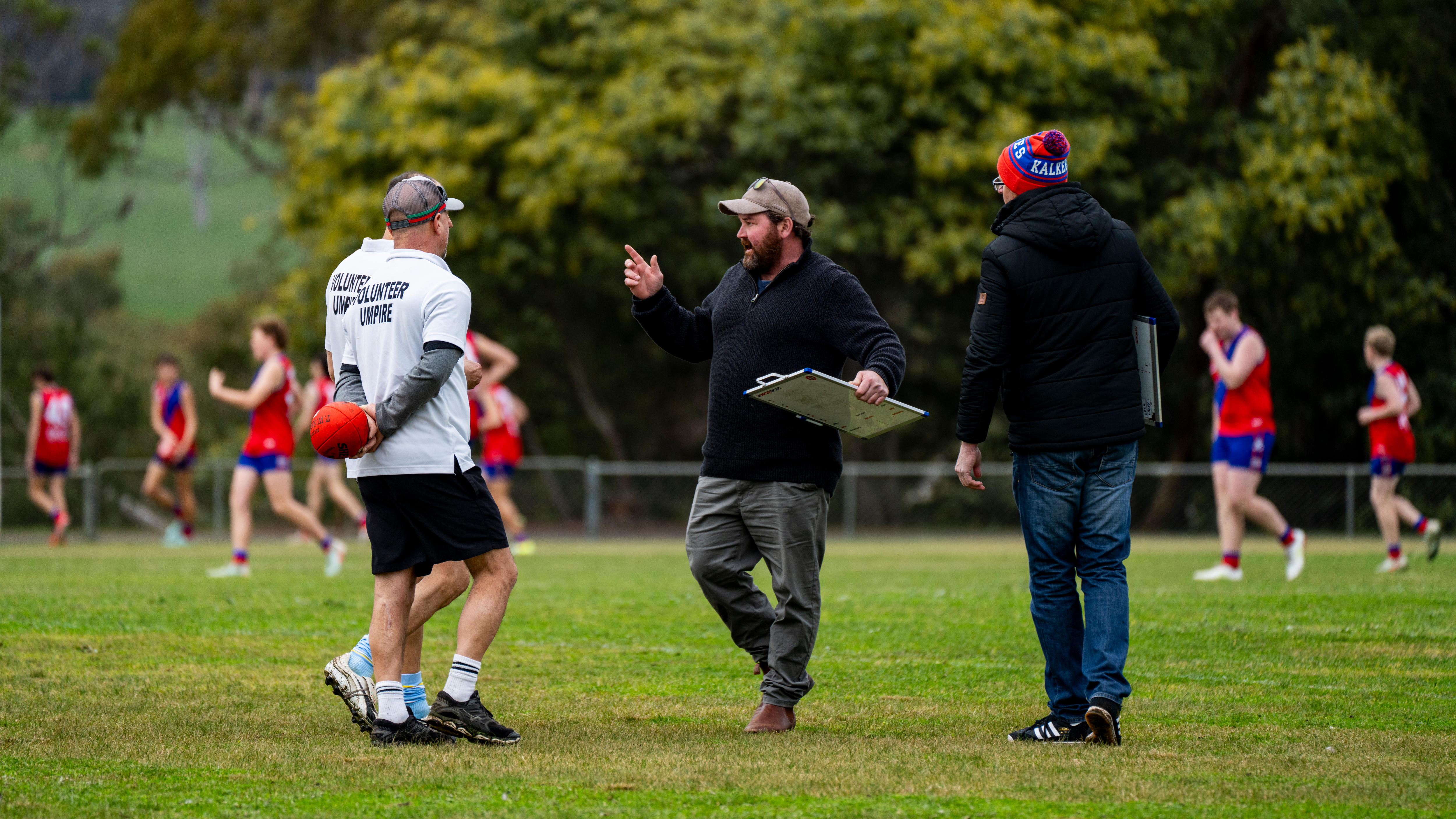 A man stands with a clipboard on a football field.