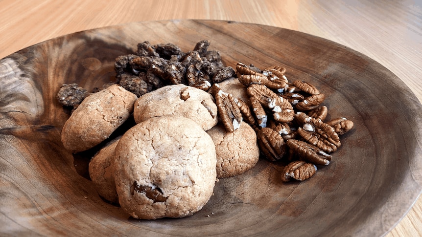 Cookies and pecans displayed on a wooden dish.