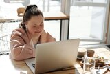 Woman working on her laptop in a cafe in a story about making career goals.