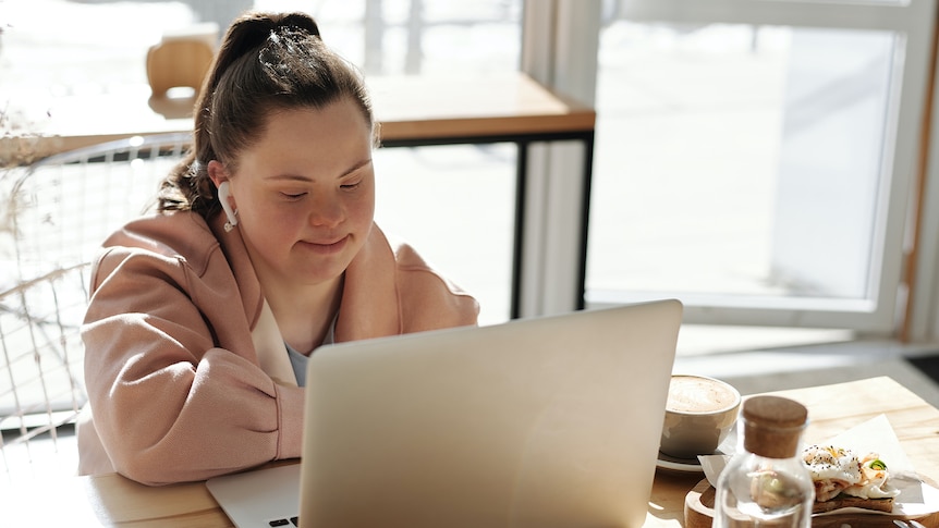 Woman working on her laptop in a cafe in a story about making career goals.