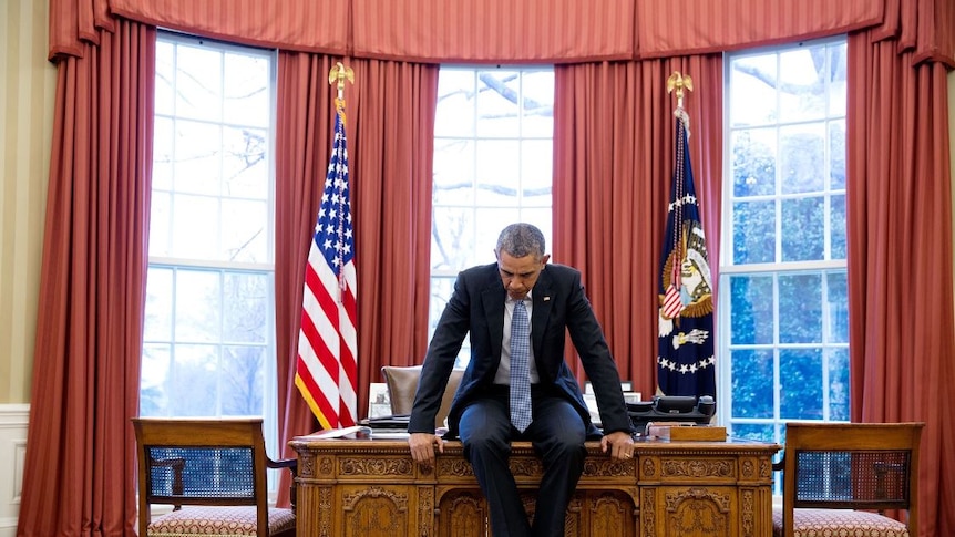 Barack Obama sits on his desk deep in thought