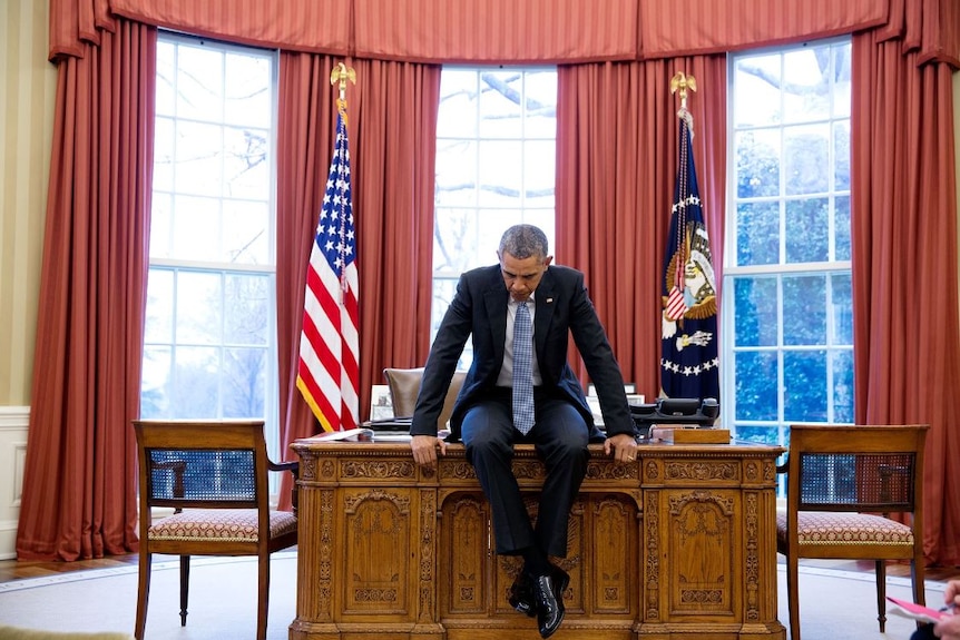 Barack Obama sits on his desk deep in thought