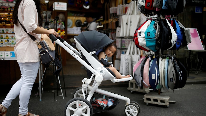 baby in pram pokes its head out to look at people.