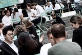 Men and women in business attire sit at an outdoor cafe.