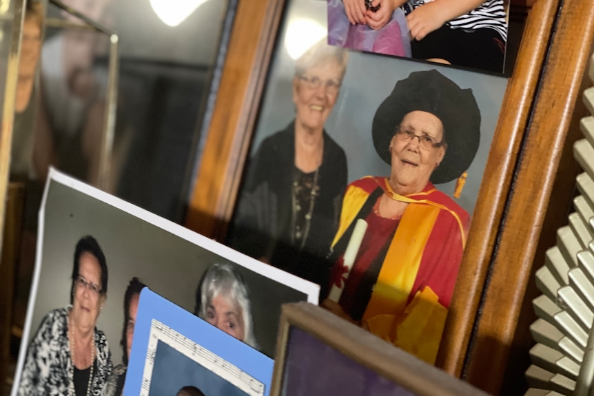 a photo of an older woman in graduation gowns, surrounded by family photos