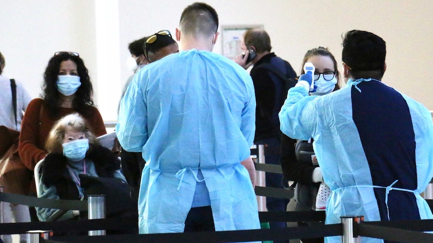 Two men dressed in protective gear prepare to test arrivals at Perth Airport.