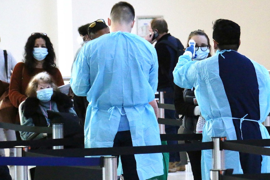 Two men dressed in protective gear prepare to test arrivals at Perth Airport.