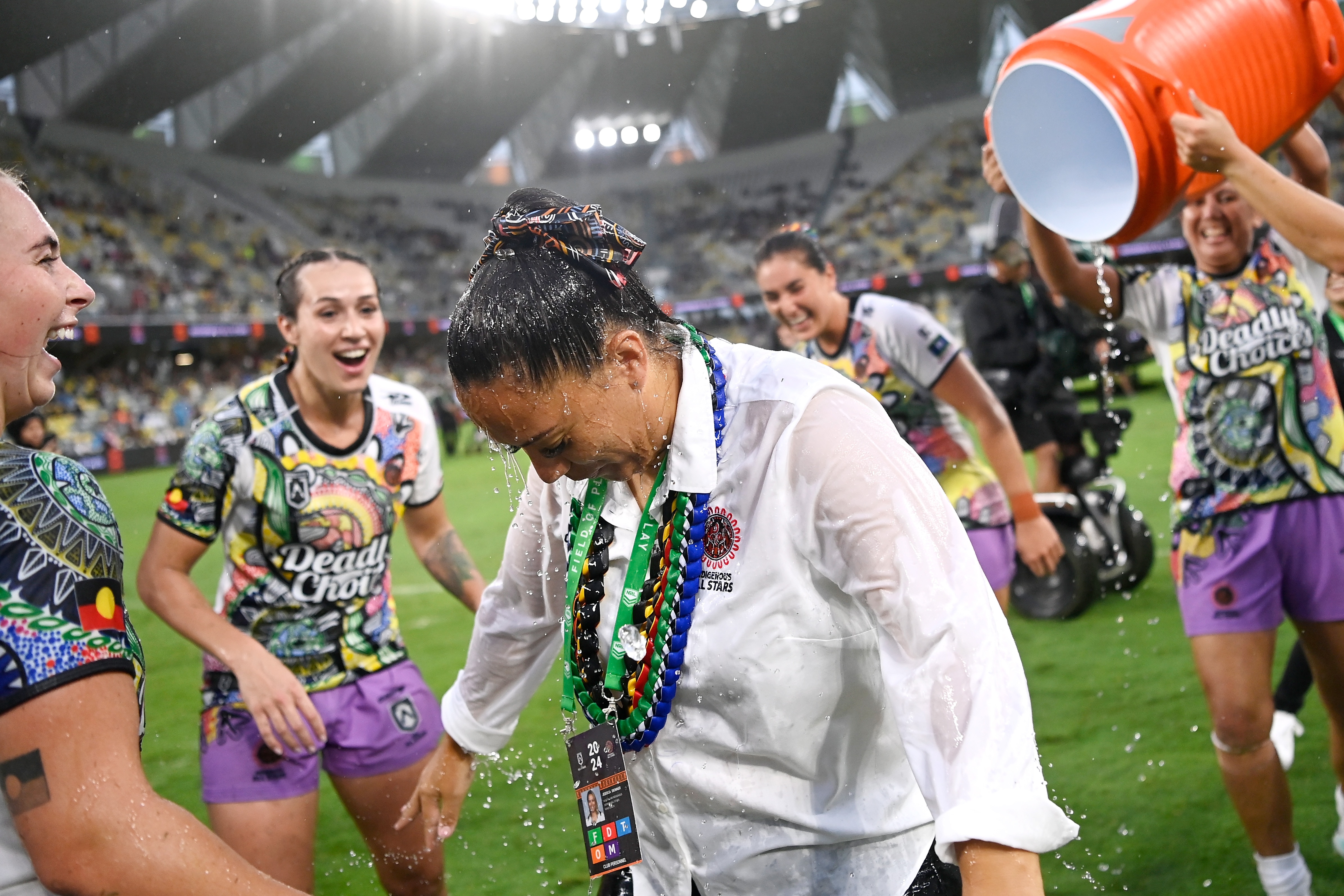 Jess Skinner has her head down and is soaked with water as players circle her and laugh.