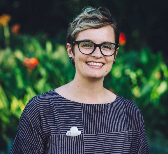 A woman in glasses smiles at the camera