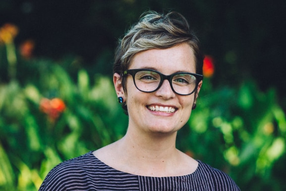 A woman in glasses smiles at the camera