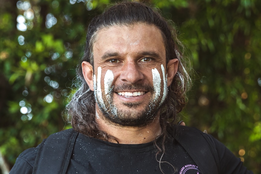 Man smiles with traditional white paint on face