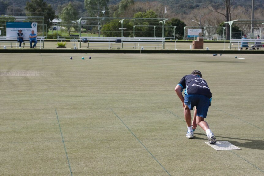 back of man playing lawn bowls
