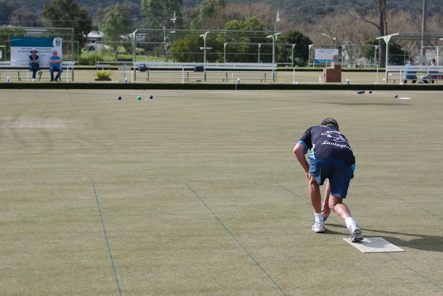 back of man playing lawn bowls