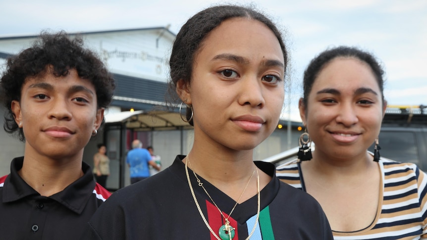 Three young people standing outside a community hall in Darwin, April 2021.