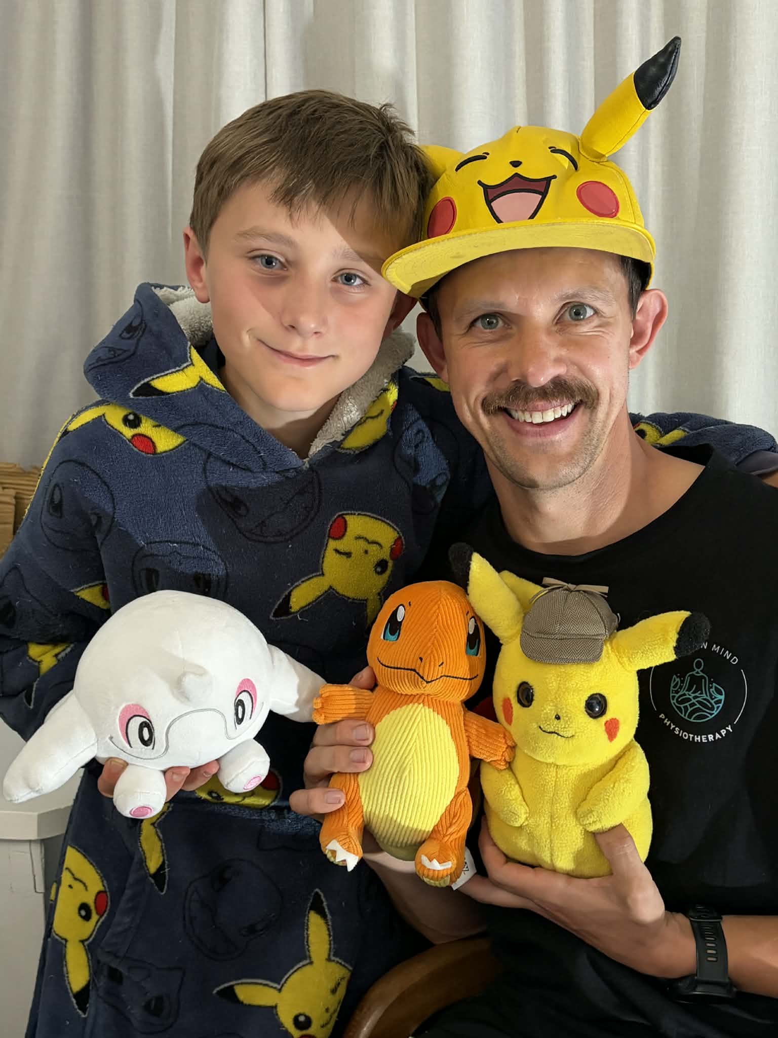 Un hombre con gorro de Pikachu de la serie Pokémon sonríe con su hijo.