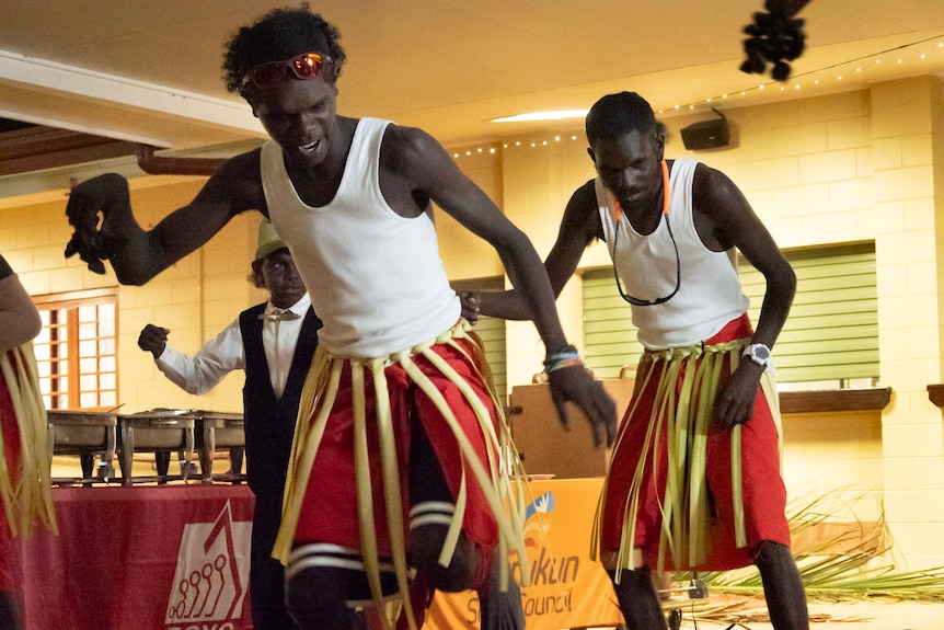 several young men in palm skirts dance