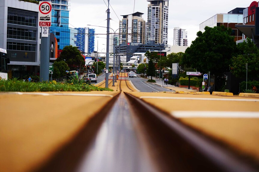 shot from the ground, these tram tracks bisect the photo, leading the eye to the road, lights and buildings in the distance