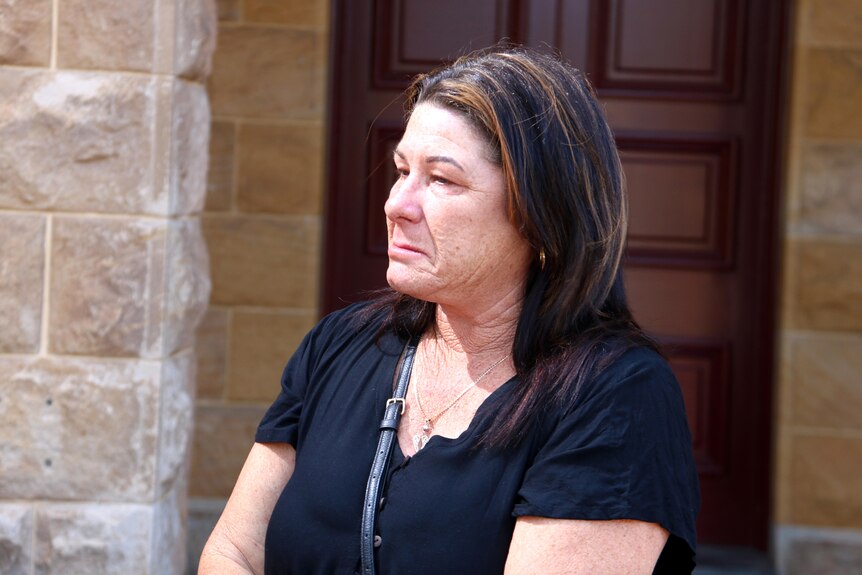 A grief-stricken woman in headshot outside a court