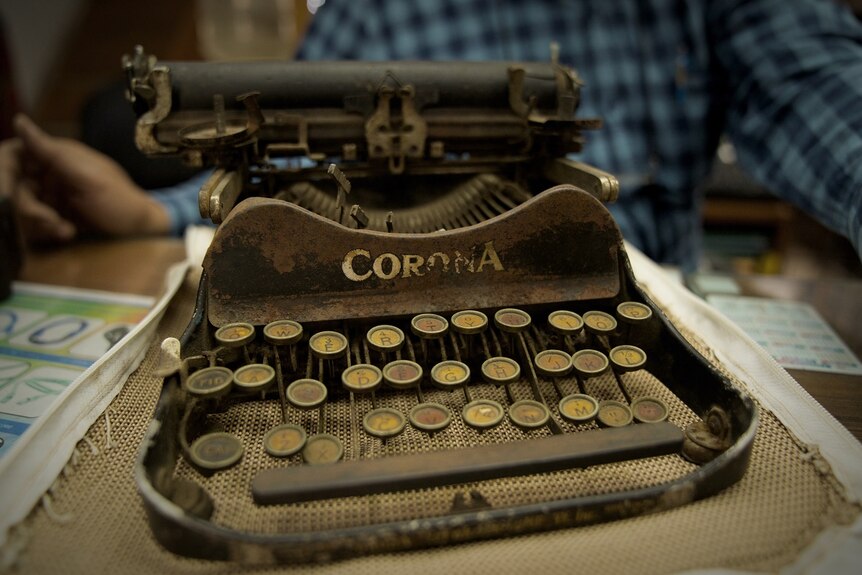 Close view of an old, golden coloured typewriter with worn, circular keys, and plenty of rust