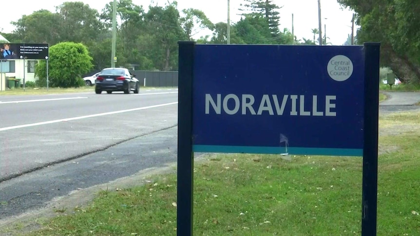 Cars can be seen in the background behind a suburb sign that reads: Noraville.