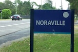 Cars can be seen in the background behind a suburb sign that reads: Noraville.