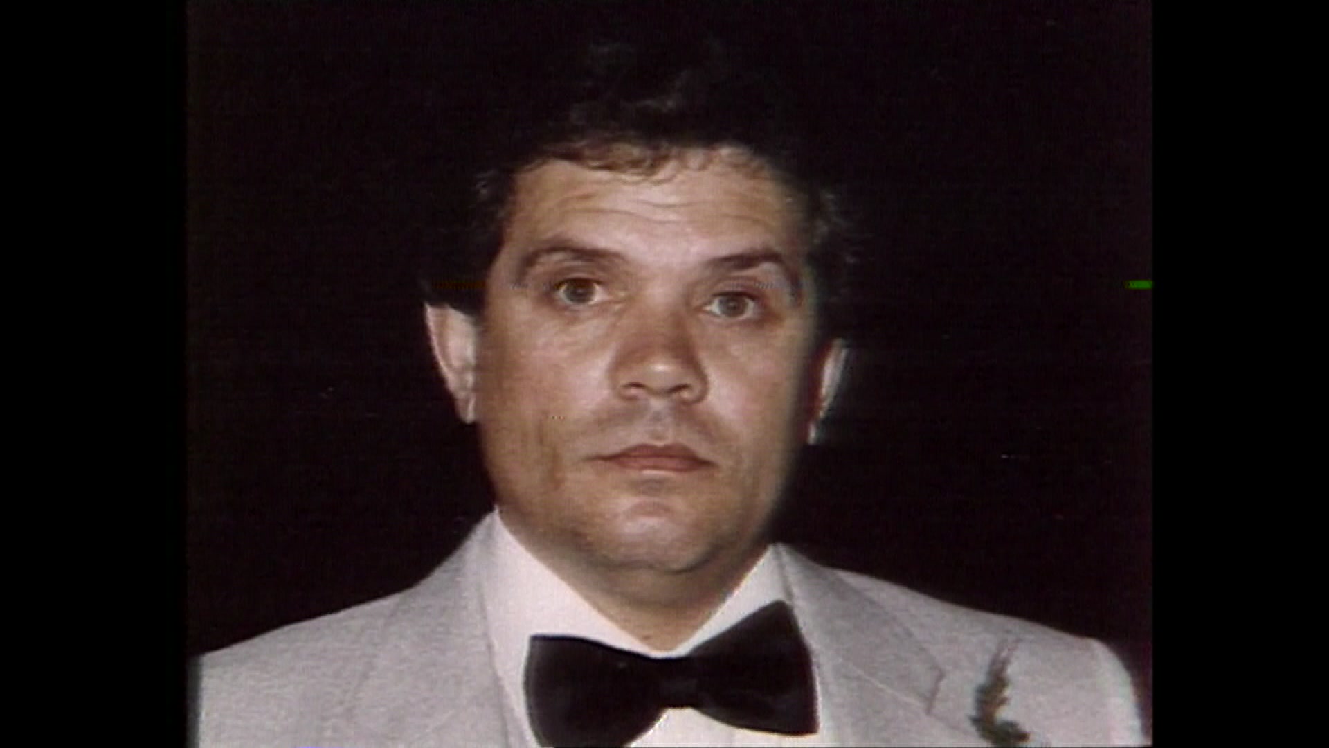 A man in a grey suit and dark bowtie