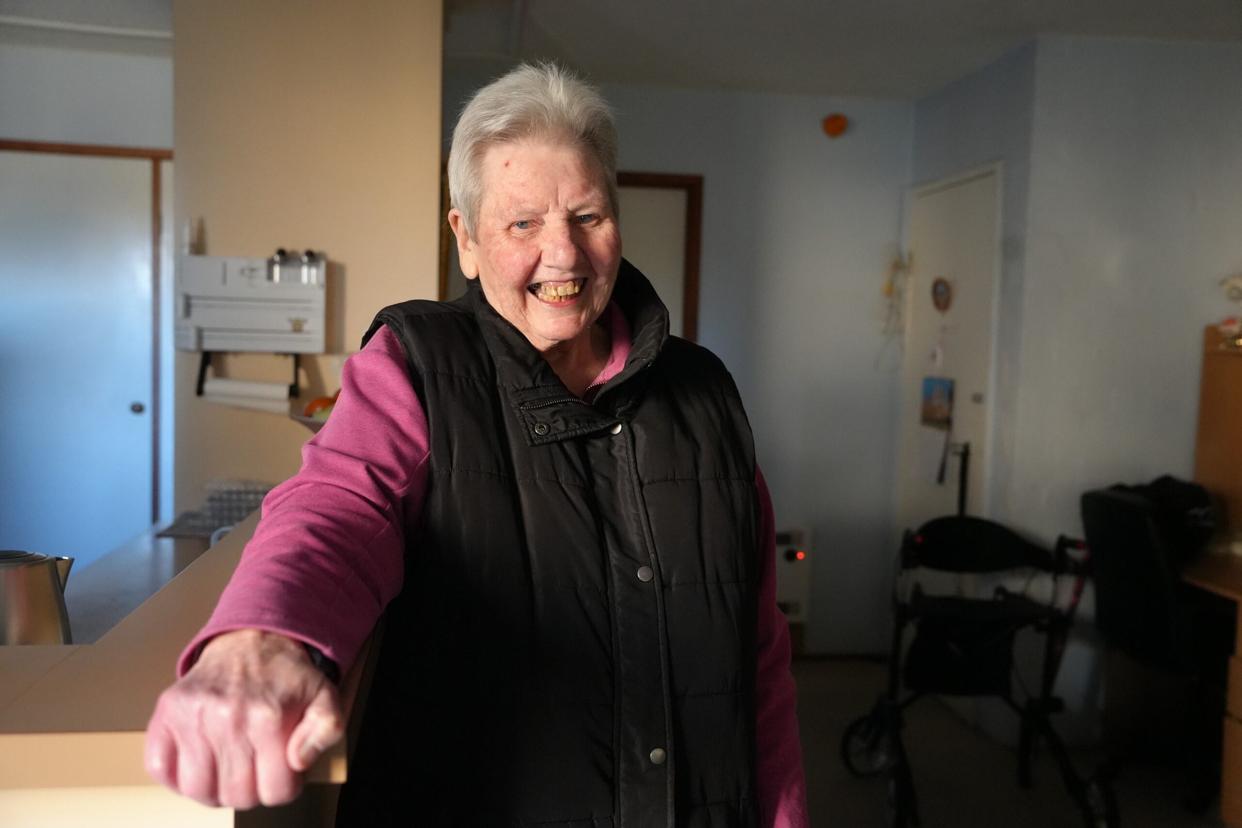 A woman in a pink sweater and black vest. 