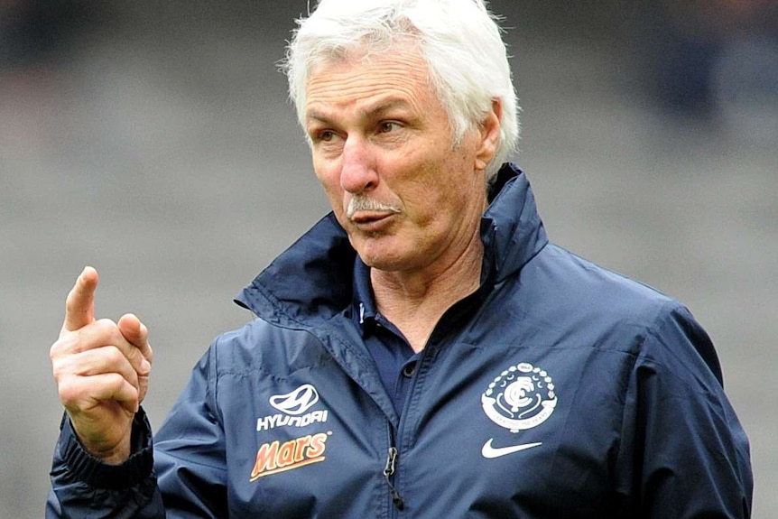 Mick Malthouse on field wearing a Collingwood tracksuit and pointing his finger.