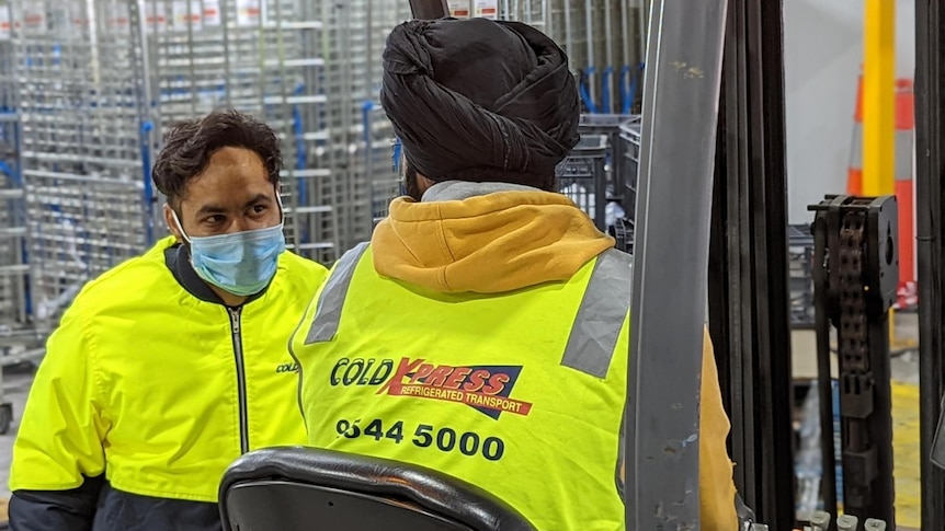 two men in hi vis in a warehouse with covid masks