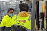 two men in hi vis in a warehouse with covid masks