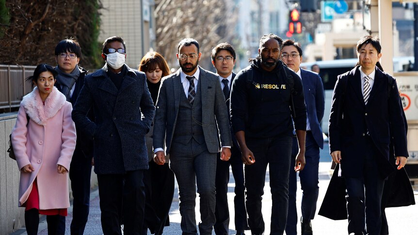 The plaintiffs in a lawsuit against Japan's police walk down a street. 