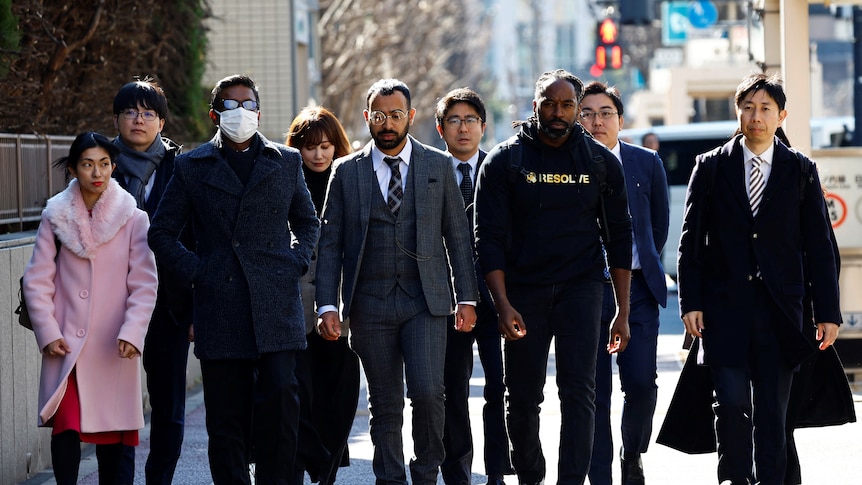 The plaintiffs in a lawsuit against Japan's police walk down a street. 