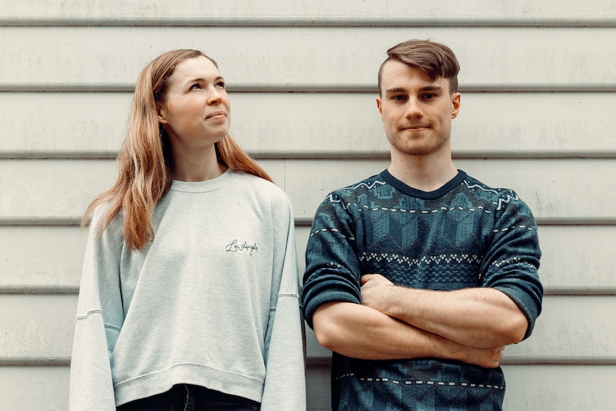 A young woman and man standing in front of a white building. 