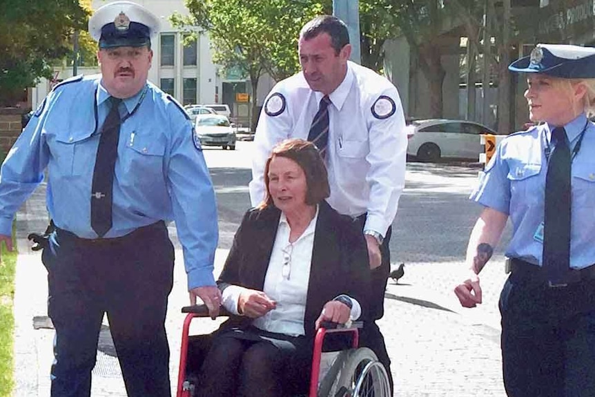 Susan Neill-Fraser in a wheel chair with police.