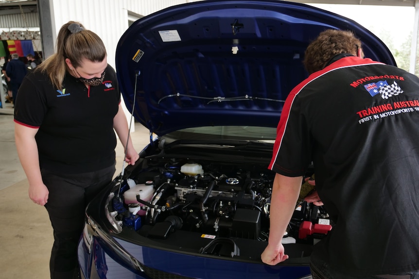 Two students look at a car engine
