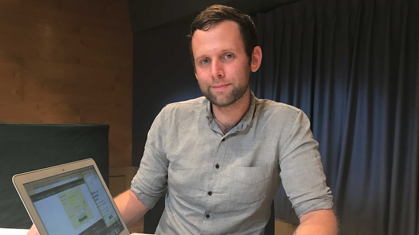 Bitcoin investor Toby Halligan sitting at a desk with an open laptop computer