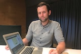 Bitcoin investor Toby Halligan sitting at a desk with an open laptop computer