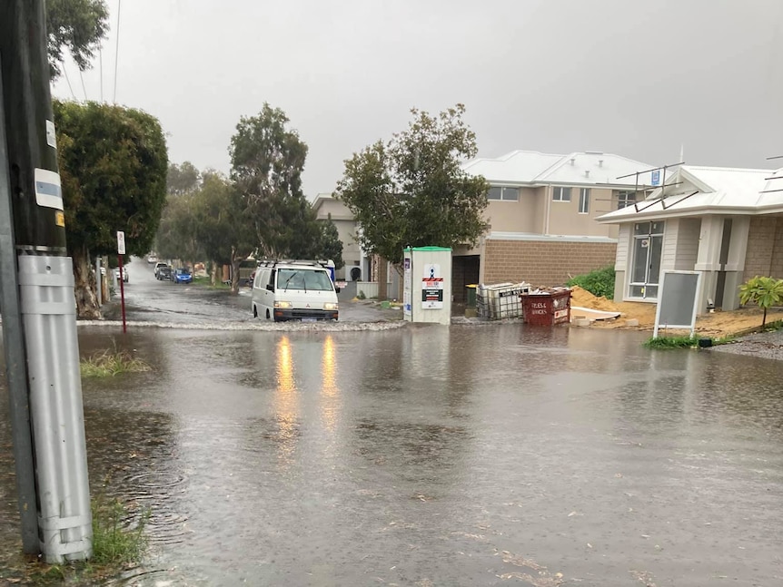 A flooded road with a white van driving through it.