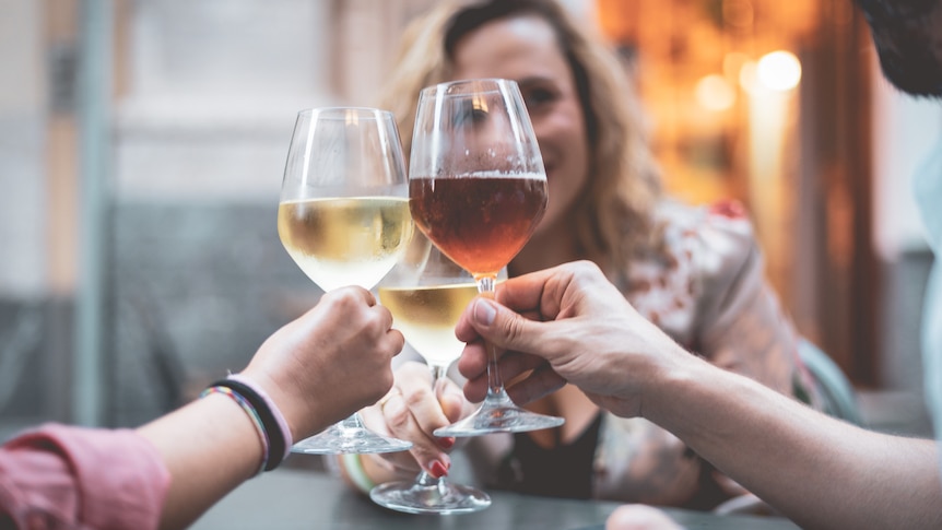 women holding up three drinks of wine