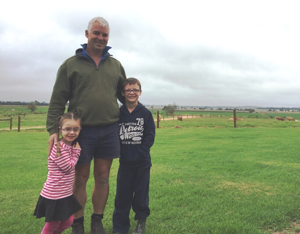 Audrey, Rohan and Harry Bingley standing in front of a green East Gippsland paddock.