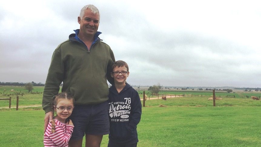 Audrey, Rohan and Harry Bingley standing in front of a green East Gippsland paddock.