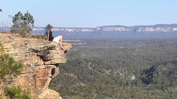 Man sits on the edge of a sandstone cliff at Boolimba Bluff, Carnarvon Gorge.