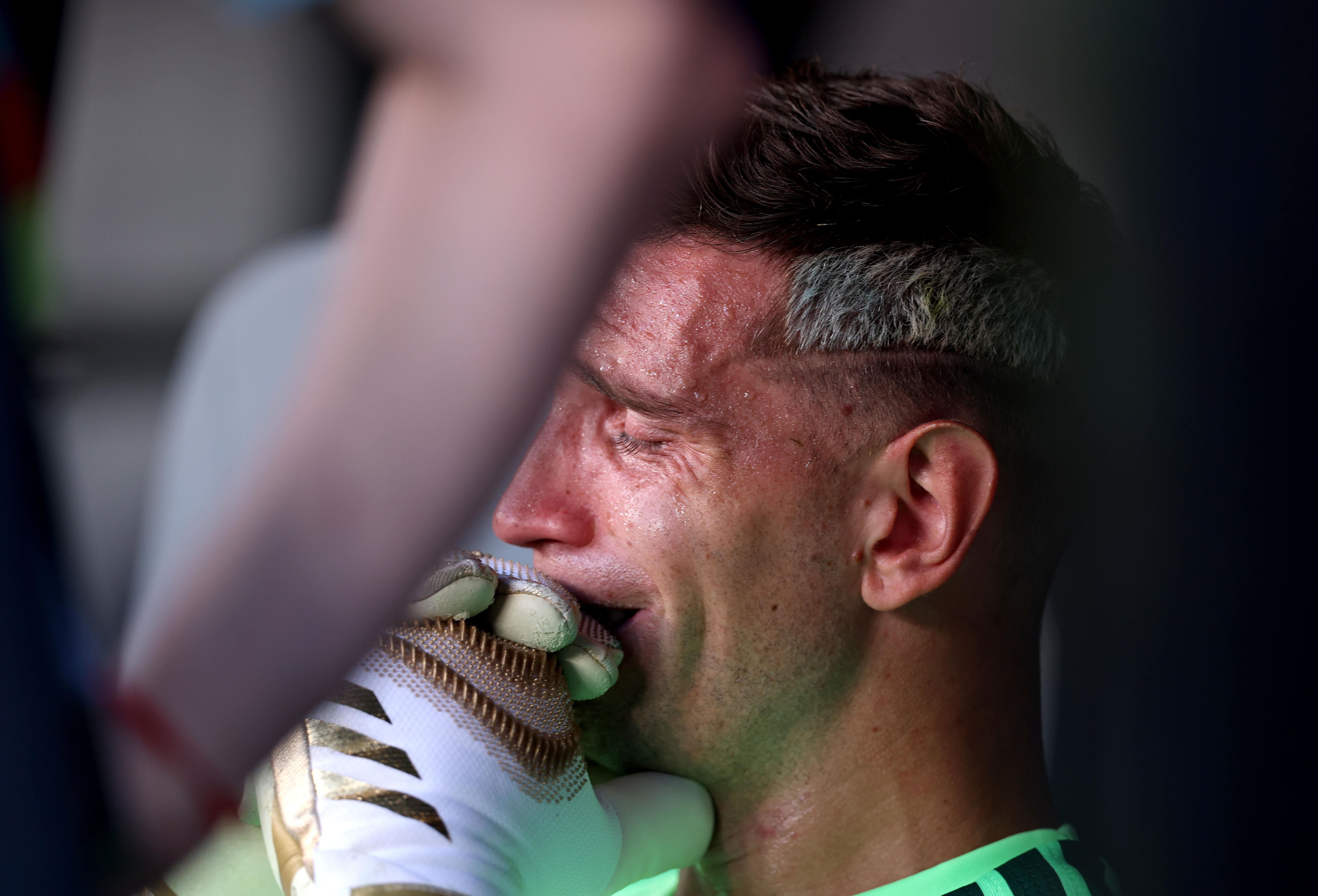 A close-up of a sweating man wearing bulky gloves, looking devastated.