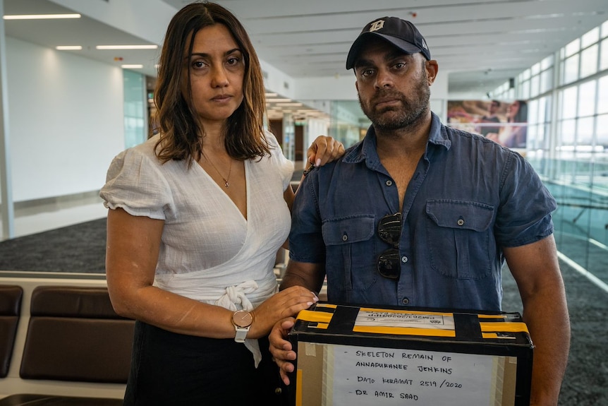 Greg Jenkins holds a box with his mother's ashes at Adelaide Airport